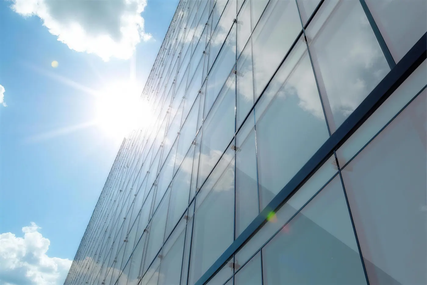 Sonne strahlt auf eine Glasfassade mit Sonnenschutzfolie